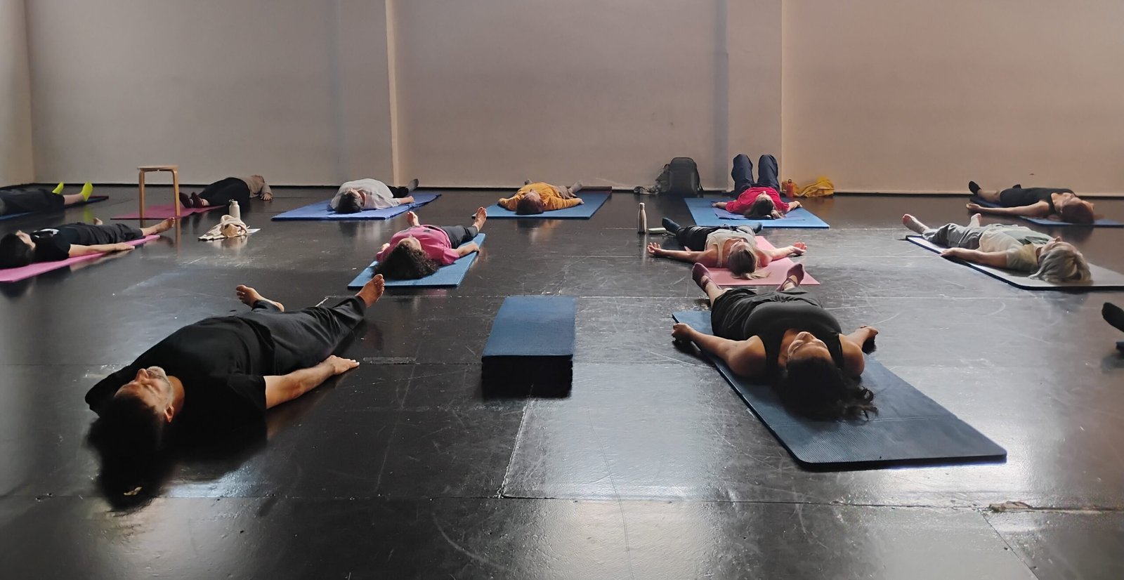 Un grupo de alumnos tumbados en el suelo sobre esterillas durante una sesión grupal de Feldenkrais, practicando la observación y la escucha interna tras una secuencia de movimiento.